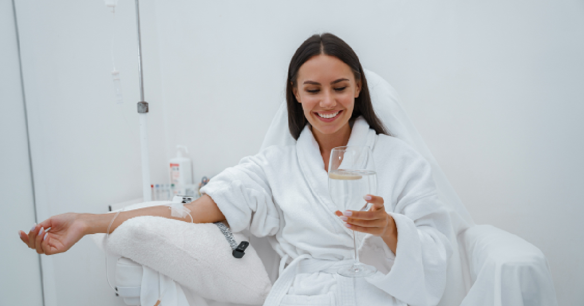 Woman relaxing with IV Hydration Therapy in Plainview, NY, sitting in a chair and holding a glass of water during treatment.